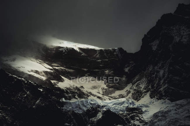 Grandes rocas pedregosas cubiertas de nieve en misteriosa neblina en el Parque Nacional Torres del Paine, Chile - foto de stock
