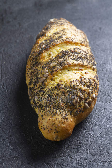 Rolo de pão fresco crocante ruivo com grãos e sementes de papoula em fundo cinza — Fotografia de Stock