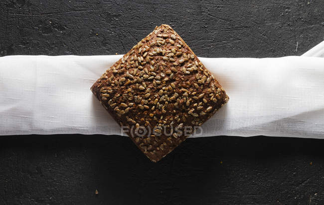 Pain biologique granuleux avec des graines sur une serviette blanche — Photo de stock