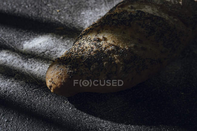 Pain de pain aux grains et graines de pavot sur fond gris à l'ombre — Photo de stock