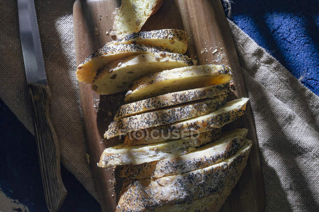 Vista superior de pão fatiado fresco servido na tábua de corte com faca no guardanapo de lona — Fotografia de Stock