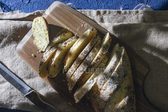 Vista superior de pão fatiado fresco servido na tábua de corte com faca no guardanapo de lona — Fotografia de Stock