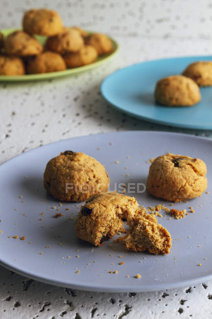Biscoitos castanhos frescos com migalhas em placas de cerâmica coloridas na mesa na cozinha — Fotografia de Stock