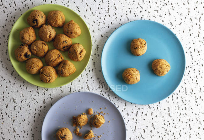 Biscoitos castanhos frescos com migalhas em placas de cerâmica coloridas na mesa na cozinha — Fotografia de Stock