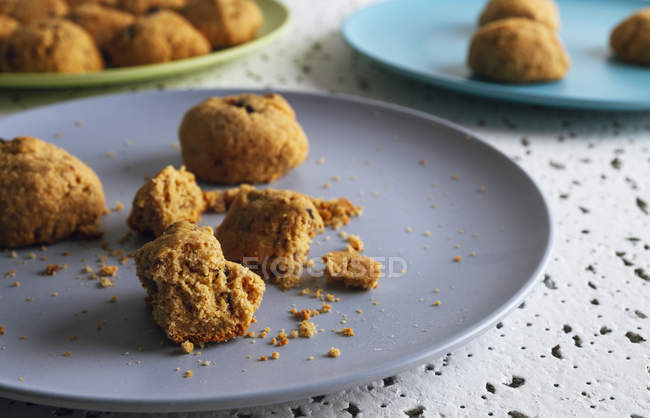 Fresh brown cookies with crumbs on colorful ceramic plates on table in kitchen — Stock Photo