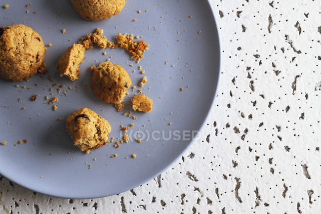 Close-up of brown cookies with crumbs on colorful ceramic plate on table in kitchen — Stock Photo