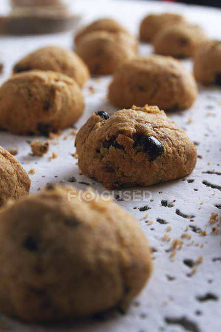 Gros plan des biscuits marrons frais faits maison avec du chocolat sur la table blanche — Photo de stock