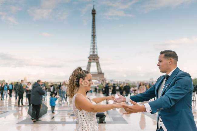 Groom in blue suit and bride in white wedding gown having slow dance smiling and looking at each other with Eiffel Tower on background at Paris — Stock Photo