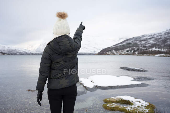 Anonymous person on pond shore against highland in winter — Stock Photo