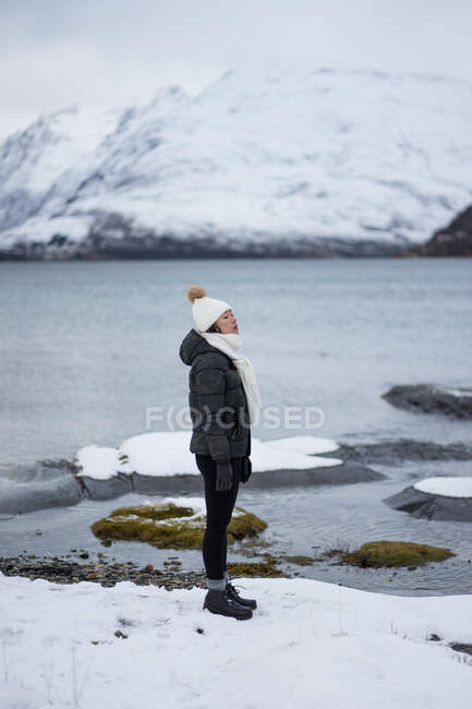 Young asian woman on pond shore against highland in winter — Stock Photo