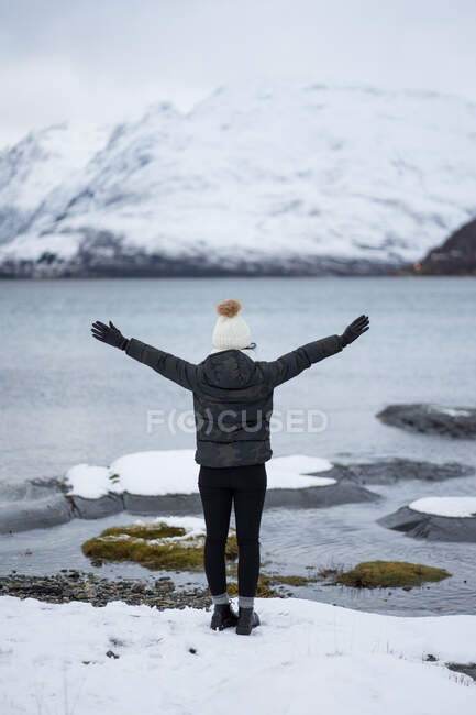 Anonymous person on pond shore against highland in winter — Stock Photo