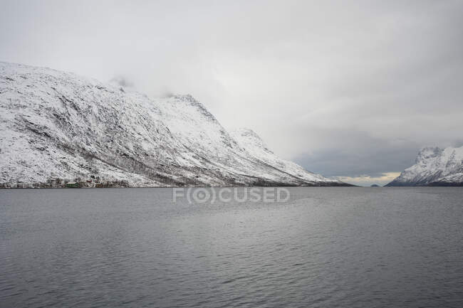 Tranquillo lago contro le colline innevate nel freddo nuvoloso — Foto stock