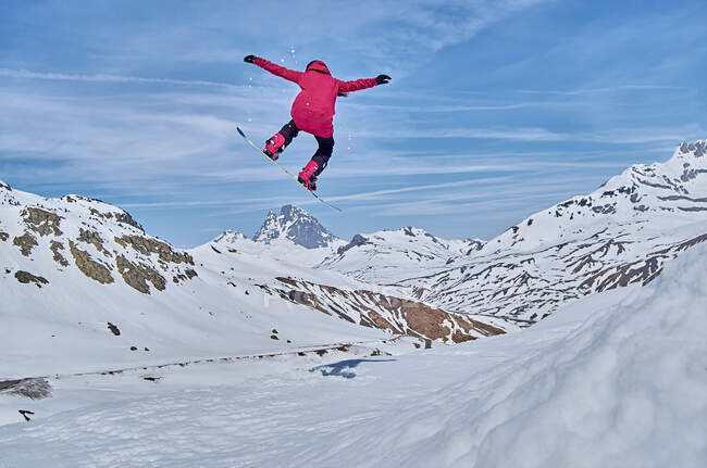 Snowboarder irreconhecível pulando na encosta — Fotografia de Stock