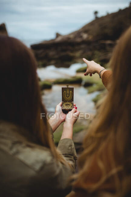 Female travelers using vintage compass with sun clock — Stock Photo