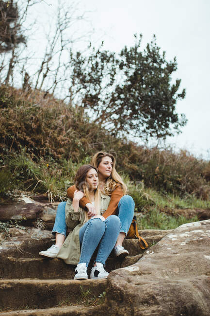 Jovens irmãs sentadas nas escadas de pedra no dia da primavera — Fotografia de Stock