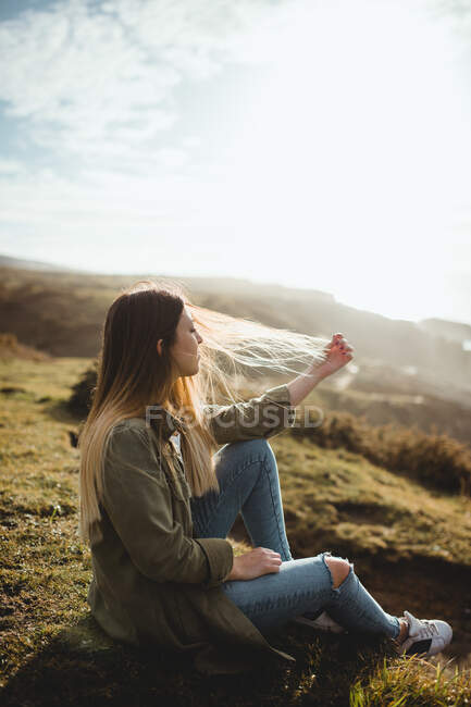 Pensive woman sitting on grass and looking at seascape — Stock Photo