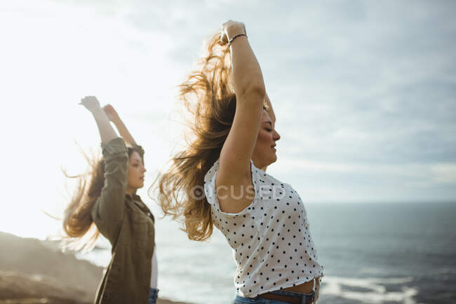 Happy female travelers enjoying freedom at seaside — Stock Photo