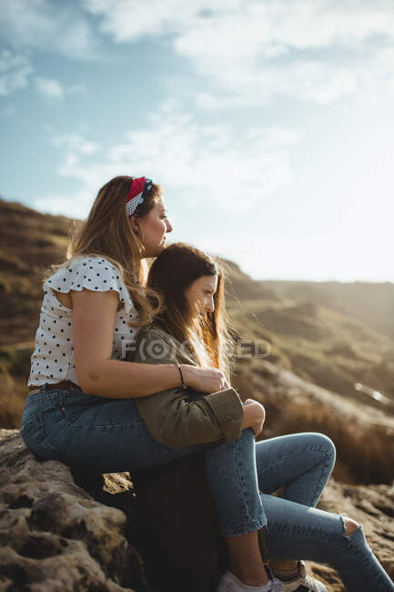 Young sisters sitting on stone on spring day — Stock Photo