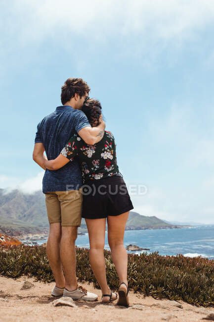 Вид сзади влюбленной прекрасной пары, отдыхающей в большом сюр-холме — стоковое фото