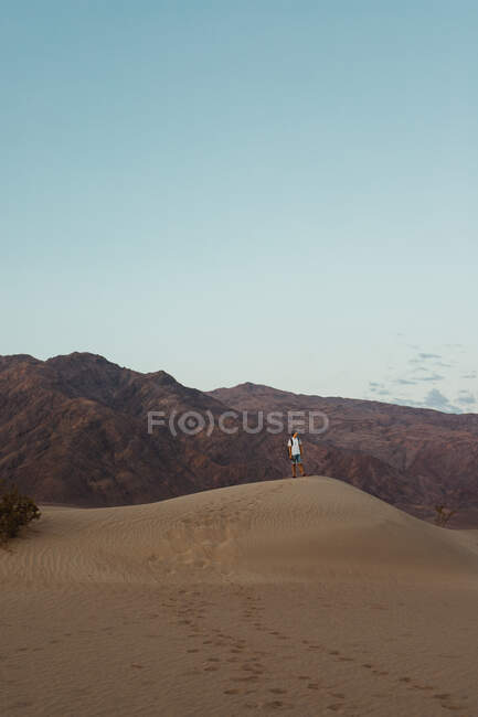 Одинокий человек, идущий по песчаной пустыне — стоковое фото