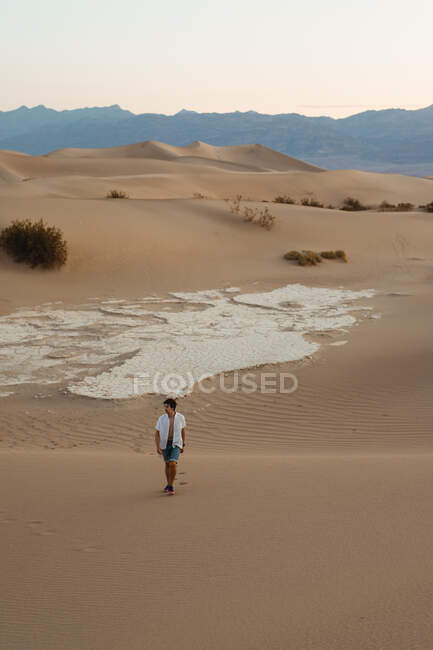 Одинокий человек, идущий по песчаной пустыне — стоковое фото