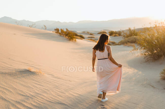 Vista posteriore della giovane donna che cammina nel deserto lasciando impronte in — Foto stock