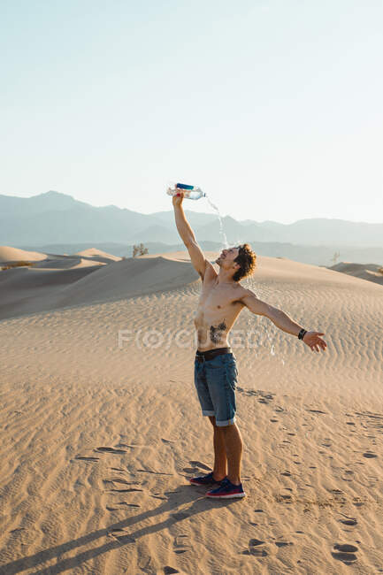 Thirsty man with naked torso drinking water stretching hands in — Stock Photo
