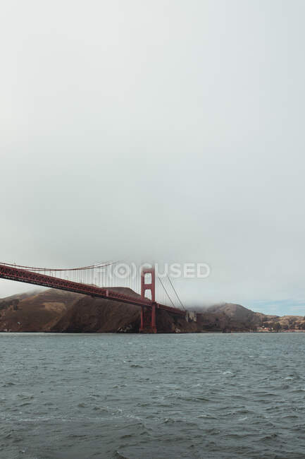 Construção da ponte vermelha sobre água escura ondulada — Fotografia de Stock