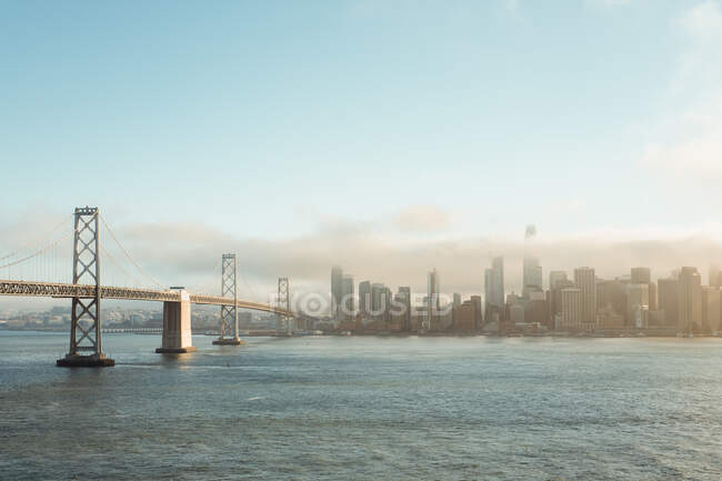 Lunga costruzione di ponti sull'acqua ondulata verso la città — Foto stock