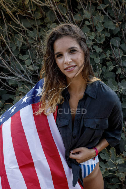 D'en haut de charmante femme avec drapeau américain sur les épaules dans le lieu de verdure — Photo de stock