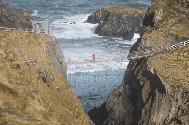 Tourist walking on rope bridge suspended between cliffs in North — Stock Photo