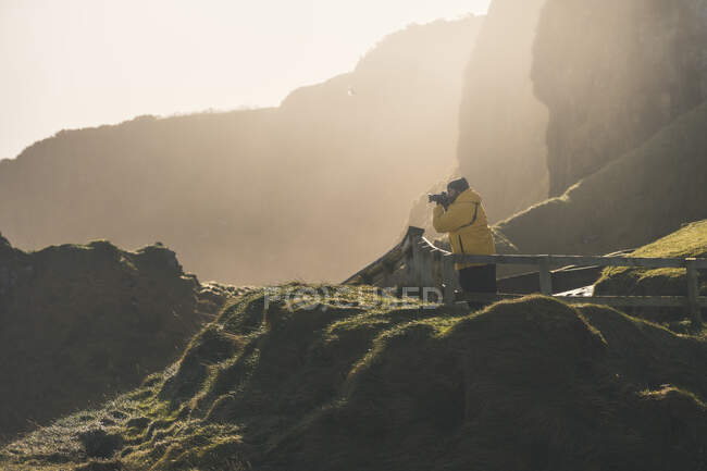 Чоловік стоїть на заміській дорозі і фотографує море з приходом — стокове фото
