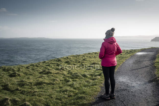 Mujer de pie en el camino del campo admirando vistas - foto de stock