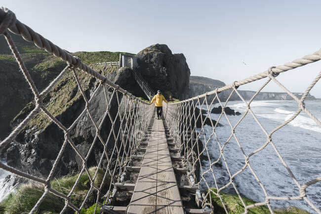 Mann überquert Seilbrücke, die zu Felseninsel führt — Stockfoto