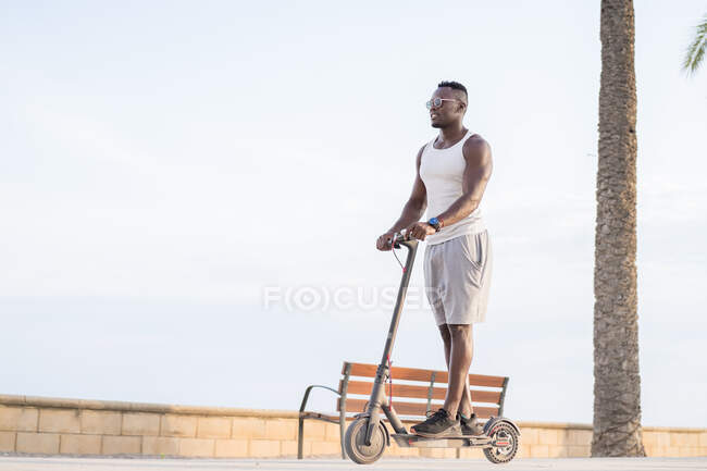 Cool adult black man riding scooter in street — Stock Photo