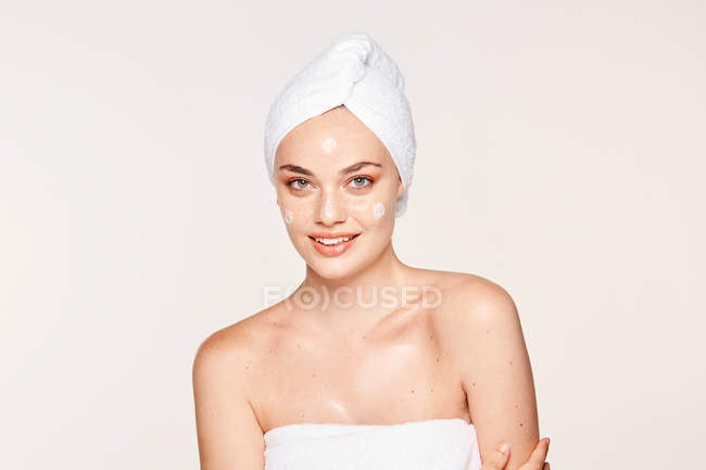 Mujer encantadora con piel radiante aplicando crema - foto de stock