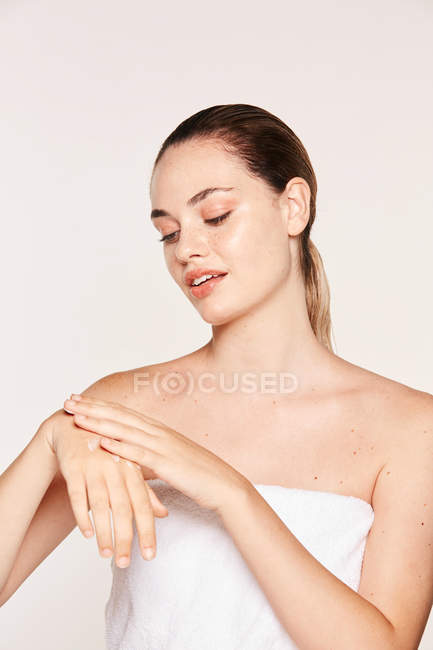 Woman in towel creaming hand with moisturizing gel isolated on white background — Stock Photo