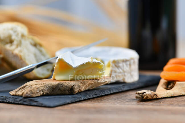 Delightful various types of white cheese and crispy fresh bread with pieces of wood on rustic table — Stock Photo