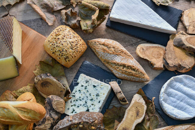 Dall'alto deliziosi vari tipi di formaggio bianco e pane fresco croccante con pezzi di legno su tavolo rustico — Foto stock