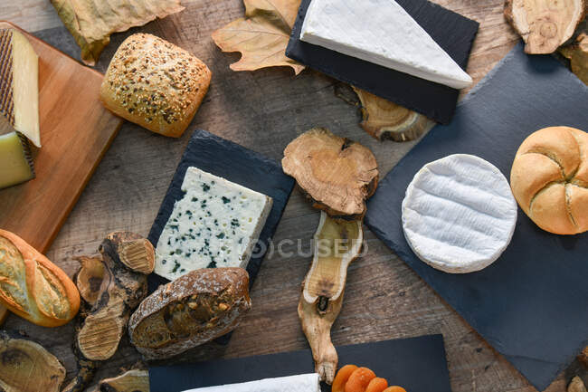 Зверху чудові різні види білого сиру і хрусткий свіжий хліб з шматочками дерева на сільському столі — стокове фото