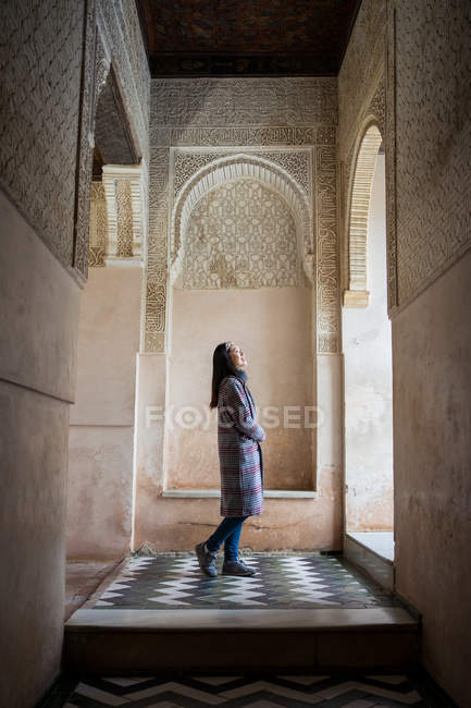 Mujer admirando la ornamentación sobre una ventana arqueada dentro del antiguo palacio islámico. - foto de stock