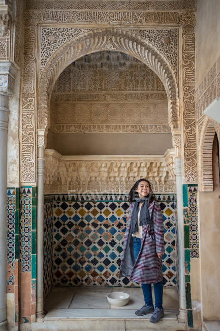 Frau bewundert Ornament über Bogen in altem islamischen Palast und blickt in Kamera — Stockfoto