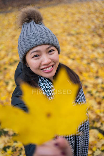 Jeune femme d'origine asiatique gaie jetant des feuilles d'érable jaunes debout dans le patio de la cathédrale d'Oslo en Norvège — Photo de stock