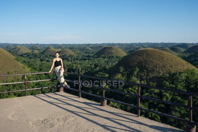 Счастливая женщина стоит на смотровой площадке на холме — стоковое фото