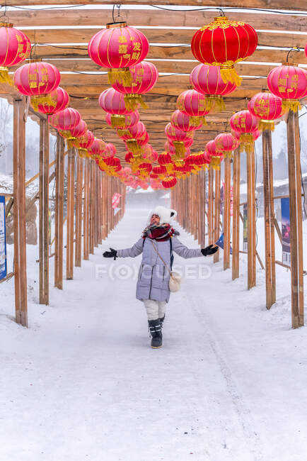 Веселая женщина идет по арке с китайскими фонарями — стоковое фото