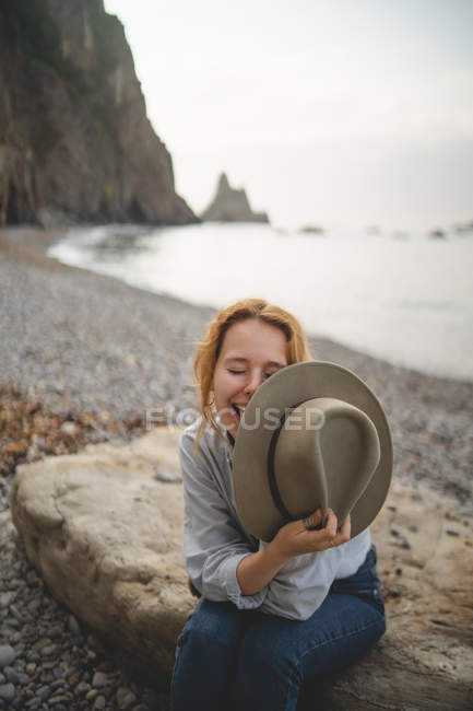 Sonhando elegante turista feminina desfrutando paisagem marinha enquanto arrefece em grande pedra na costa rochosa das Astúrias olhando para longe — Fotografia de Stock