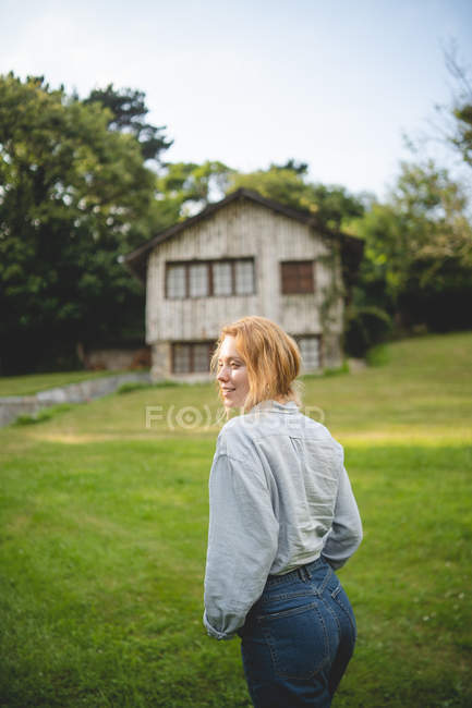 Vista lateral da calma casual jovem que gosta de passear no prado verde perto de casa de madeira na aldeia rural em Astúrias, Espanha — Fotografia de Stock