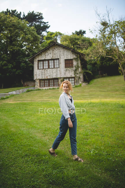 Vista lateral da calma casual jovem que gosta de passear no prado verde perto de casa de madeira na aldeia rural em Astúrias, Espanha — Fotografia de Stock