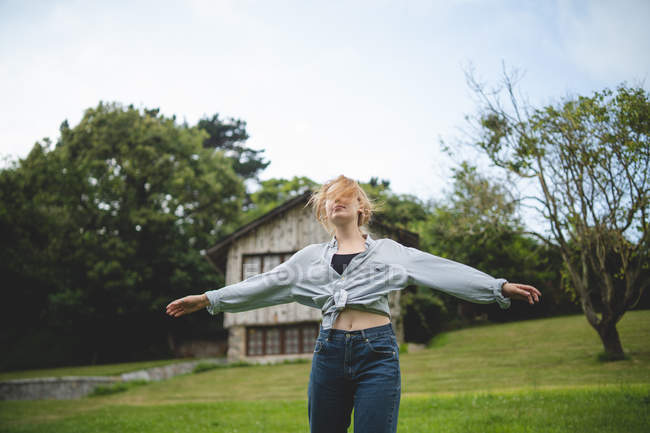 Casual calm young woman dancing enjoying stroll on green meadow near wooden house in rural village in Asturias, Spain — Stock Photo