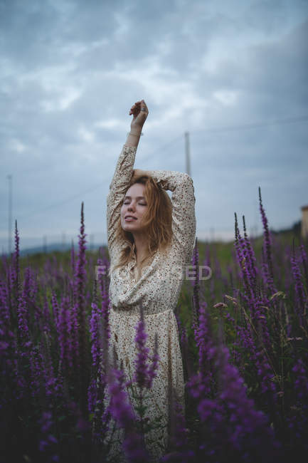 Happy sensual tender redhead woman with closed eyes enjoying smell of salvia blossom in meadow of Asturias, Spain — Stock Photo